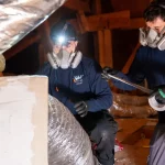 Technicians repair ductwork in the attic